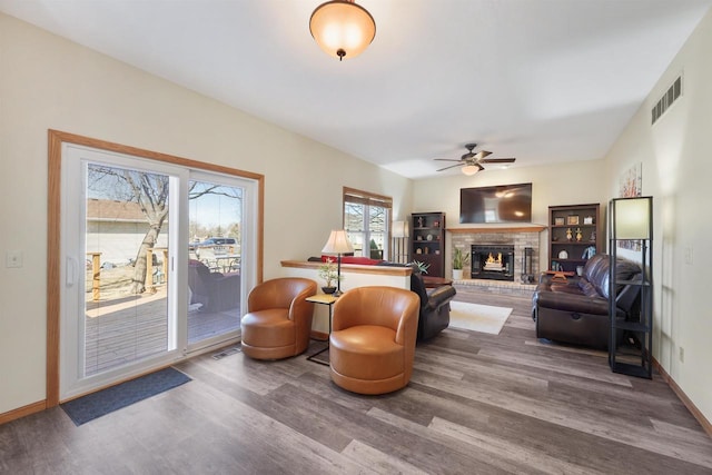 sitting room with visible vents, a ceiling fan, wood finished floors, a fireplace, and baseboards