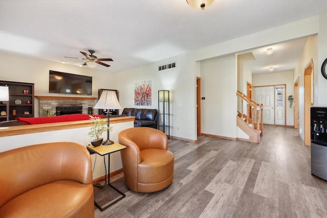 living area featuring visible vents, wood finished floors, stairway, a fireplace, and baseboards