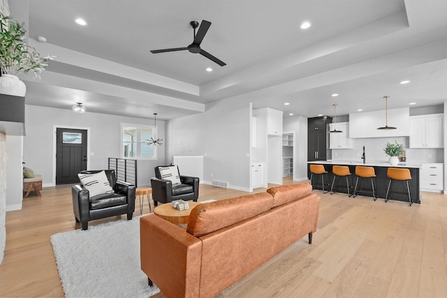 living room with recessed lighting, a raised ceiling, visible vents, light wood-type flooring, and baseboards