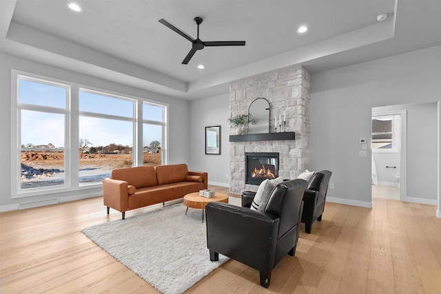 living area with light wood-type flooring, a raised ceiling, visible vents, and a fireplace