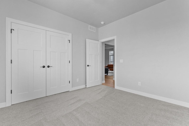 unfurnished bedroom featuring baseboards, a closet, visible vents, and light colored carpet