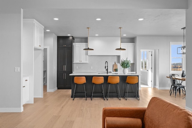 kitchen featuring hanging light fixtures, a kitchen breakfast bar, light countertops, and an island with sink