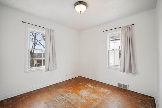 empty room with visible vents, baseboards, and wood finished floors