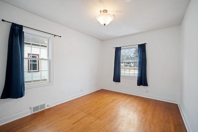 spare room with visible vents, baseboards, and wood finished floors