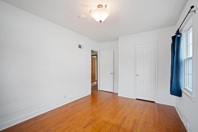 unfurnished bedroom with visible vents, baseboards, and wood finished floors