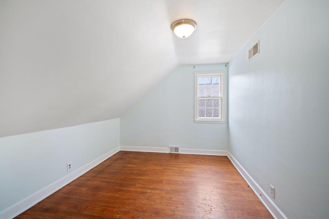 bonus room with dark wood-style flooring, visible vents, vaulted ceiling, and baseboards