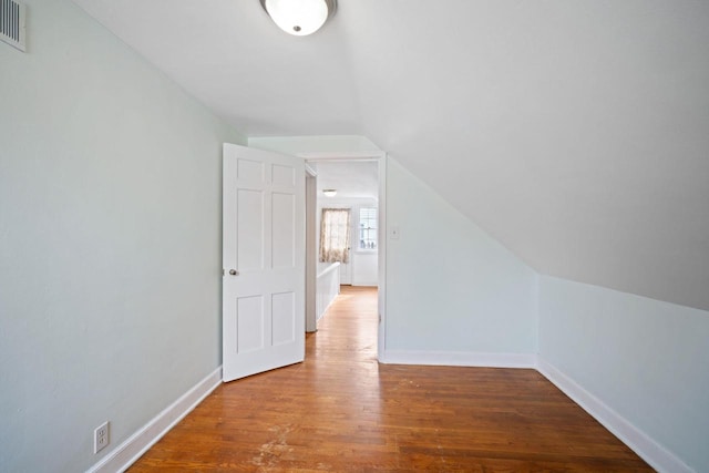 additional living space featuring lofted ceiling, visible vents, baseboards, and wood finished floors