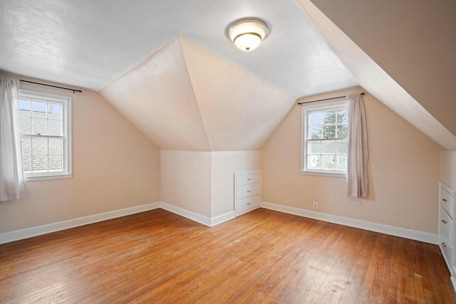 bonus room featuring vaulted ceiling, light wood finished floors, and baseboards