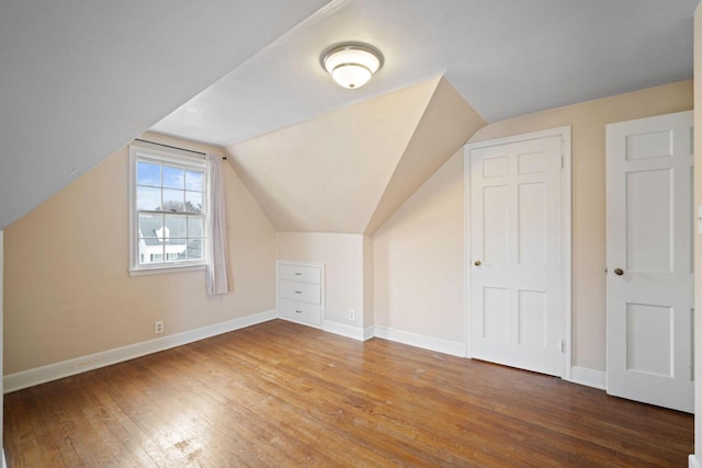 bonus room with vaulted ceiling, wood finished floors, and baseboards