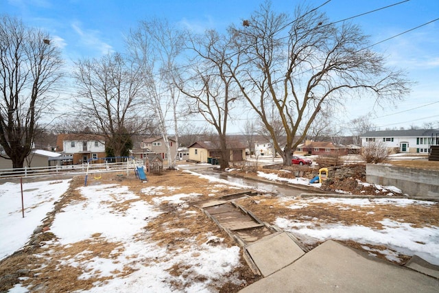 yard layered in snow featuring fence and a residential view