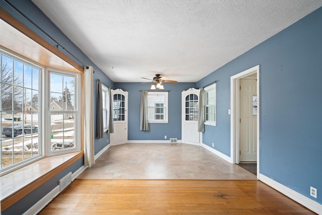 spare room with light wood-type flooring, plenty of natural light, visible vents, and baseboards