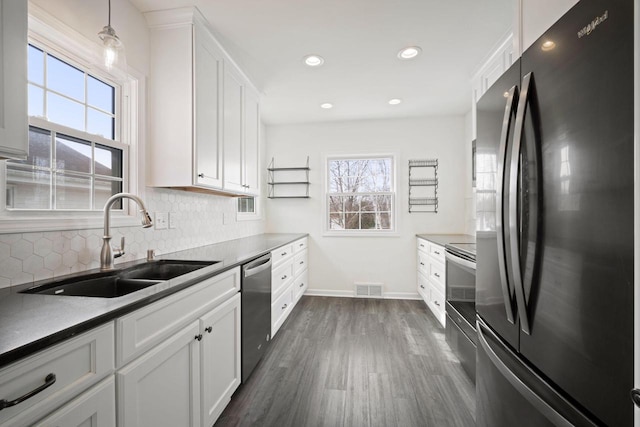 kitchen with freestanding refrigerator, white cabinets, decorative light fixtures, and dark countertops