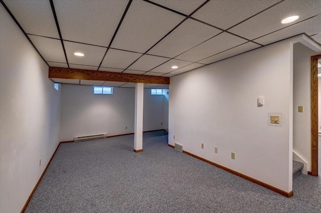 basement with a paneled ceiling, visible vents, a baseboard heating unit, and carpet flooring