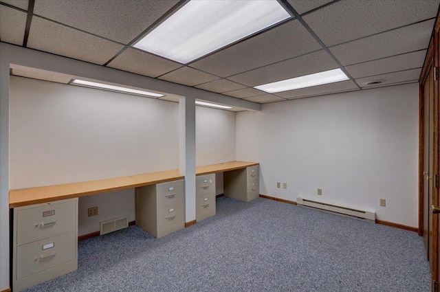 unfurnished office featuring a baseboard radiator, a paneled ceiling, carpet floors, visible vents, and built in desk