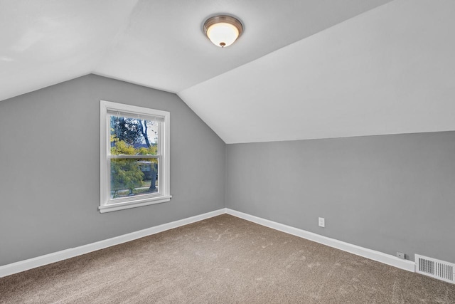 additional living space featuring carpet, visible vents, vaulted ceiling, and baseboards