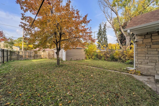 view of yard with an outbuilding, a fenced backyard, and a shed