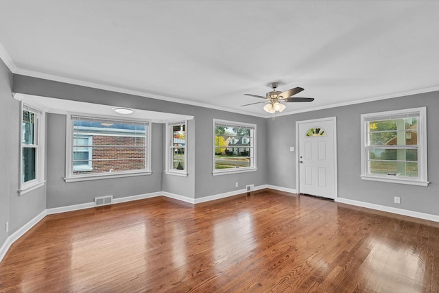 foyer entrance with ceiling fan, wood finished floors, visible vents, baseboards, and crown molding