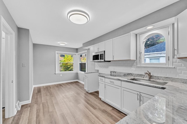 kitchen with stainless steel microwave, white cabinetry, and decorative backsplash