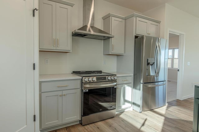 kitchen featuring stainless steel appliances, light countertops, light wood-style flooring, and wall chimney exhaust hood