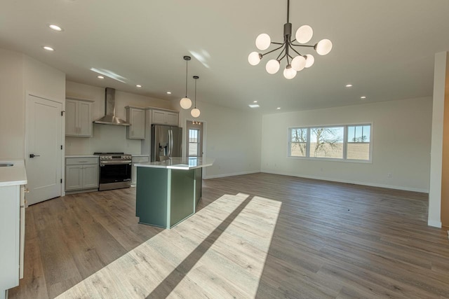 kitchen with a center island, stainless steel appliances, light countertops, light wood-type flooring, and wall chimney exhaust hood