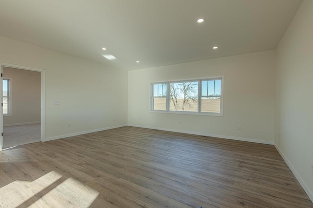 spare room featuring baseboards, wood finished floors, and recessed lighting