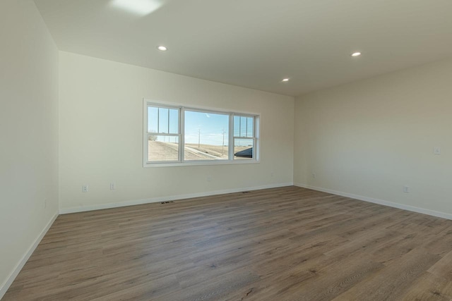 spare room featuring recessed lighting, baseboards, and wood finished floors