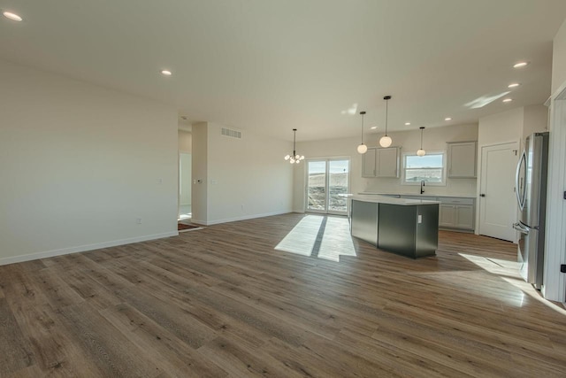 kitchen featuring a sink, visible vents, open floor plan, freestanding refrigerator, and a center island