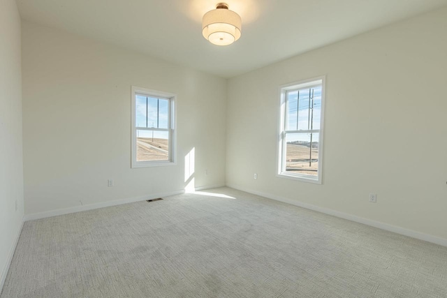 carpeted empty room featuring visible vents, a wealth of natural light, and baseboards