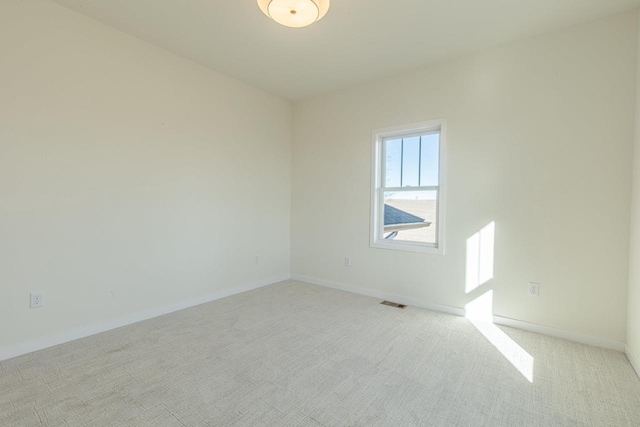 empty room featuring baseboards, visible vents, and light colored carpet