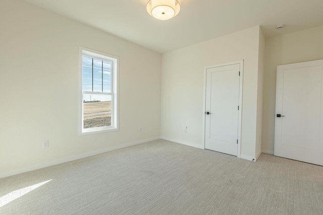 unfurnished bedroom featuring light carpet and baseboards