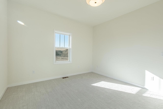 spare room with light carpet, visible vents, and baseboards