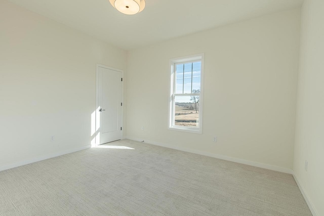 spare room featuring light colored carpet and baseboards