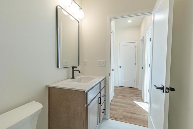 bathroom featuring toilet, wood finished floors, and vanity