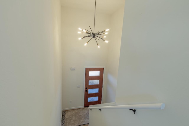 foyer entrance featuring carpet floors, an inviting chandelier, and baseboards