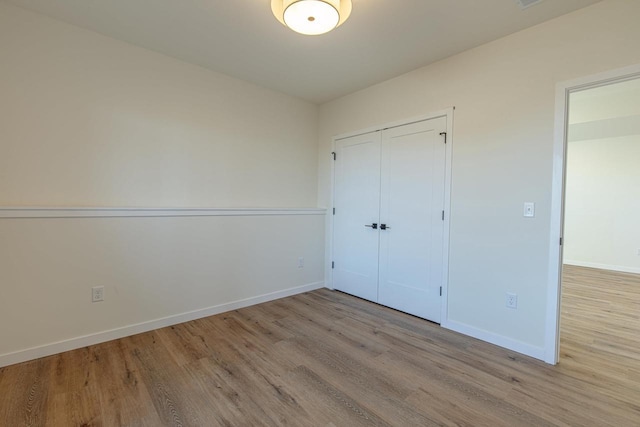 unfurnished bedroom with a closet, baseboards, and wood finished floors