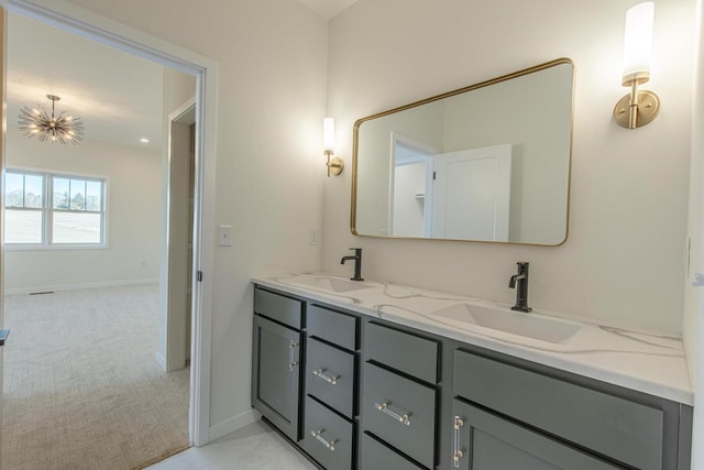 full bathroom with double vanity, an inviting chandelier, a sink, and baseboards