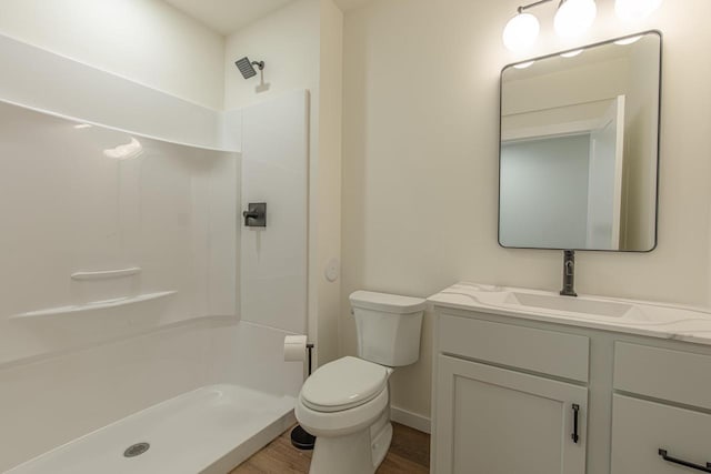 bathroom featuring a shower, wood finished floors, vanity, and toilet