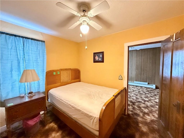 bedroom with a baseboard heating unit, dark colored carpet, and a ceiling fan