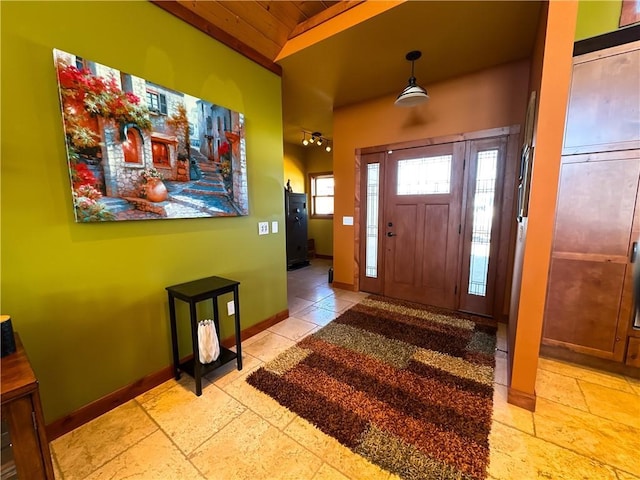 entrance foyer with vaulted ceiling, stone tile flooring, wood ceiling, and baseboards