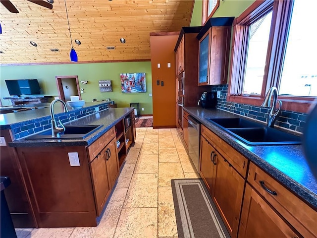 kitchen with dark countertops, stainless steel dishwasher, glass insert cabinets, and a sink