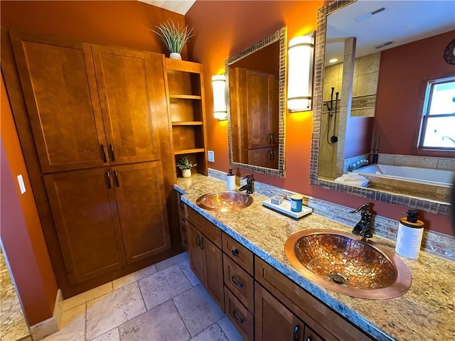 bathroom featuring stone tile flooring, a garden tub, a tile shower, and a sink