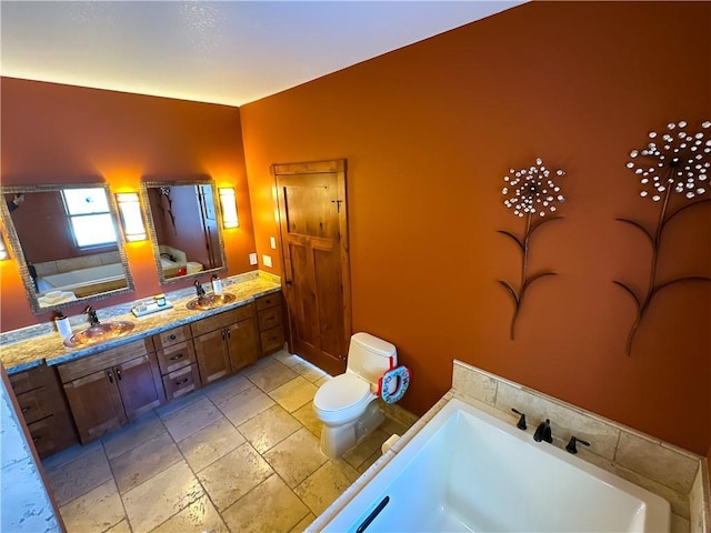 bathroom featuring a sink, double vanity, a garden tub, and toilet