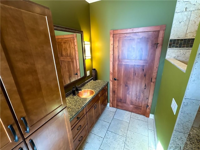 bathroom with stone tile flooring and vanity