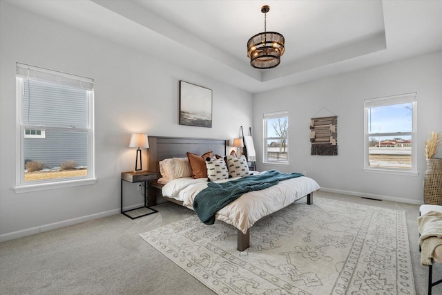 carpeted bedroom featuring a chandelier, baseboards, and a raised ceiling