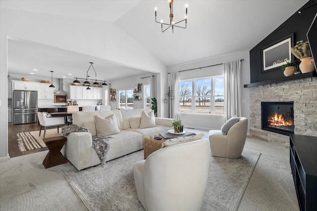 carpeted living area with a chandelier, a stone fireplace, and vaulted ceiling