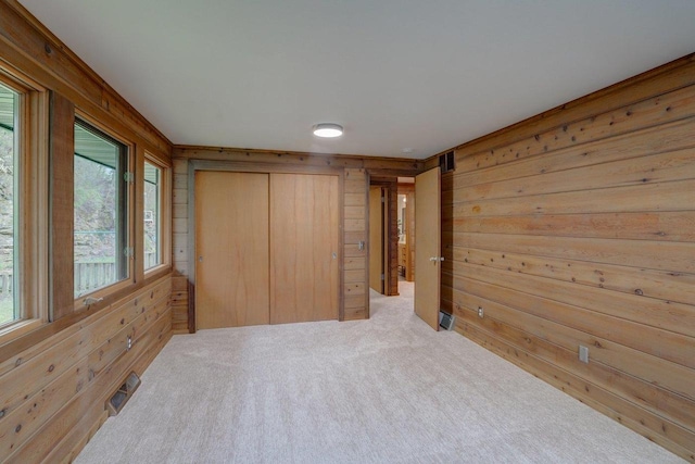 carpeted bedroom with visible vents, wood walls, a closet, and multiple windows