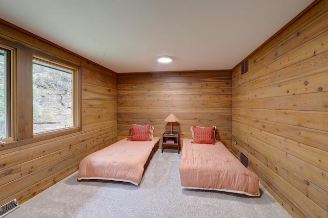 bedroom with wooden walls, visible vents, and carpet