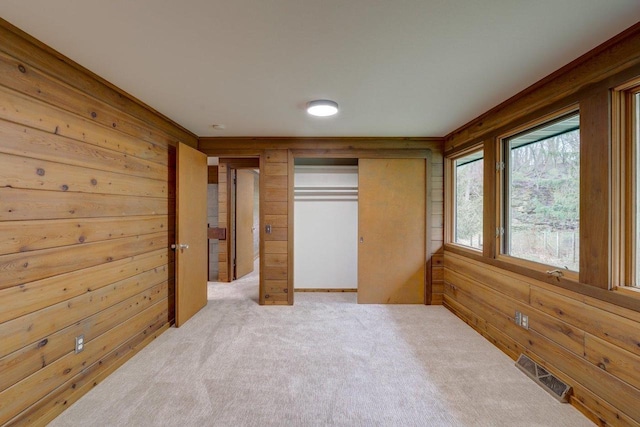 unfurnished bedroom featuring a closet, carpet floors, visible vents, and wood walls