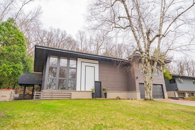 view of front of home featuring an attached garage, driveway, stairs, and a front yard