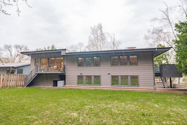 back of property featuring fence, a wooden deck, a yard, and stairs